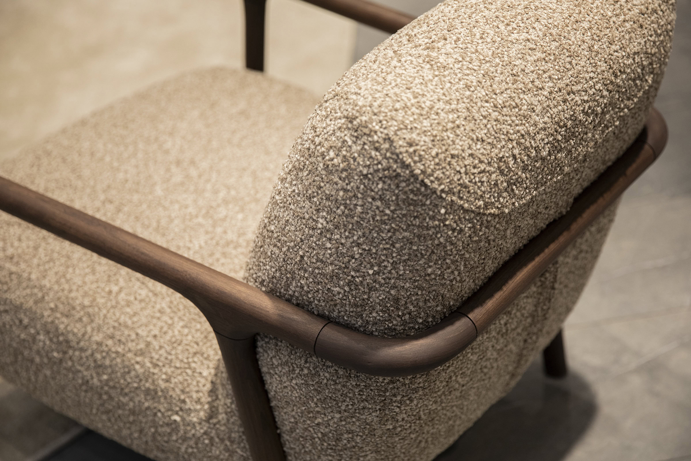 Cozy beige textured armchair with wooden armrests and frame, showcasing modern furniture design and comfort. Perfect for stylish living room or lounge areas.