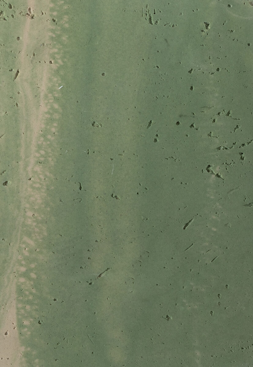 Rustic green concrete surface with textured details and small holes, ideal for modern furniture and interior design projects.