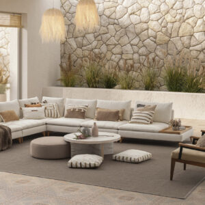 Stylish living room featuring a large white sectional sofa, cozy armchairs, and decorative cushions, complemented by natural stone wall accents and lush indoor plants for a warm, inviting atmosphere.